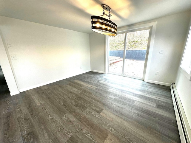 unfurnished dining area featuring a wealth of natural light, dark hardwood / wood-style flooring, a notable chandelier, and a baseboard heating unit