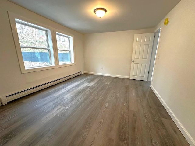 unfurnished room with dark wood-type flooring and a baseboard heating unit