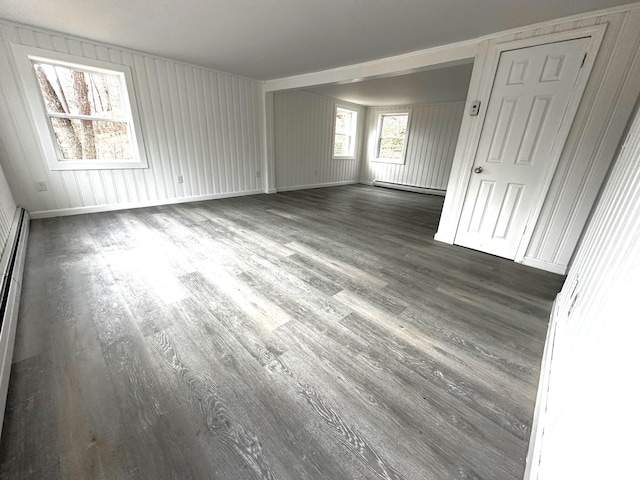 empty room featuring dark wood-type flooring and a baseboard heating unit