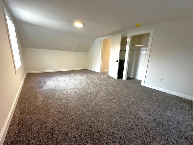 bonus room with dark colored carpet and lofted ceiling