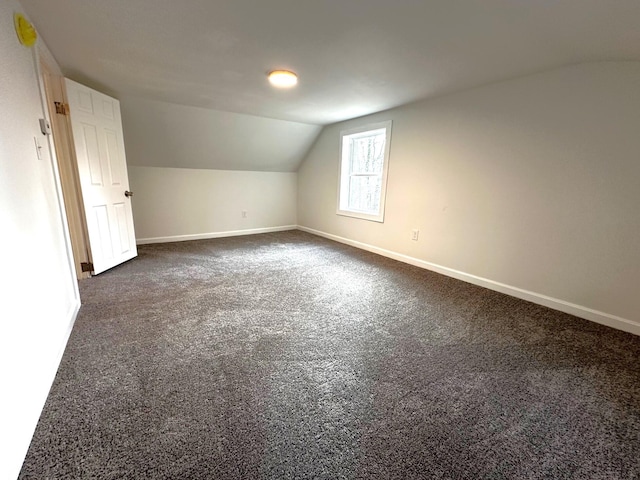 bonus room featuring lofted ceiling and dark colored carpet