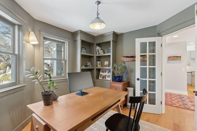 office space with a healthy amount of sunlight, french doors, and light hardwood / wood-style flooring