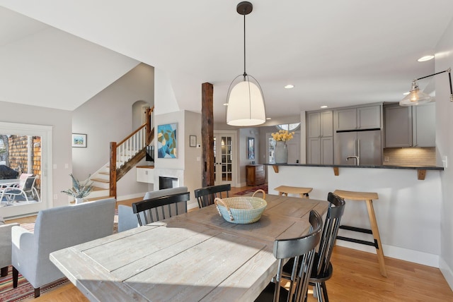 dining area with light wood-type flooring and vaulted ceiling