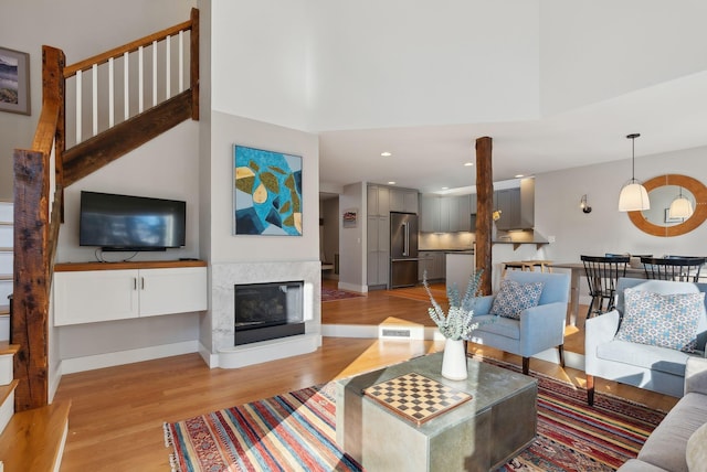 living room featuring a towering ceiling, a multi sided fireplace, and light hardwood / wood-style floors