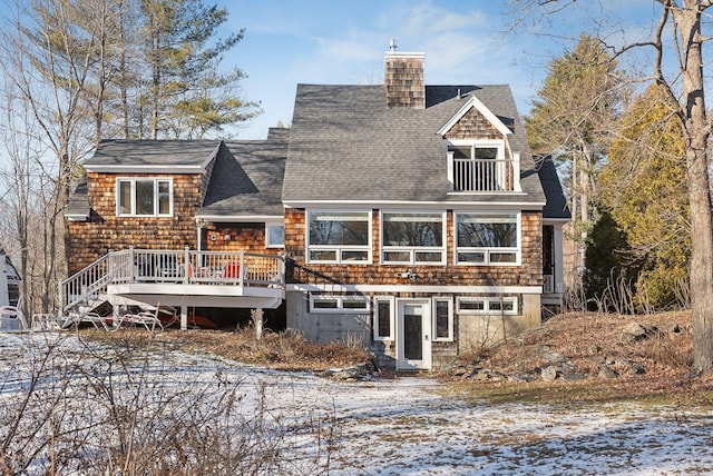 snow covered back of property featuring a wooden deck