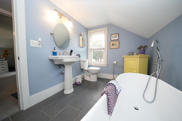 bathroom with toilet, a tub, and vaulted ceiling