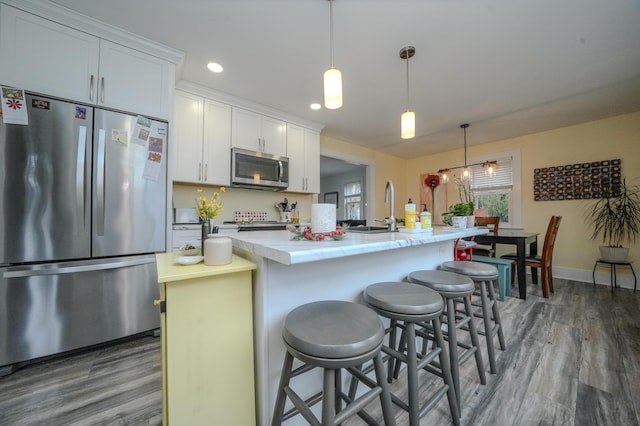 kitchen with a kitchen breakfast bar, a center island with sink, appliances with stainless steel finishes, sink, and white cabinetry