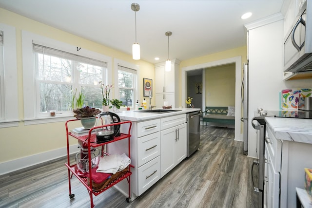 kitchen with sink, stainless steel appliances, white cabinetry, and pendant lighting