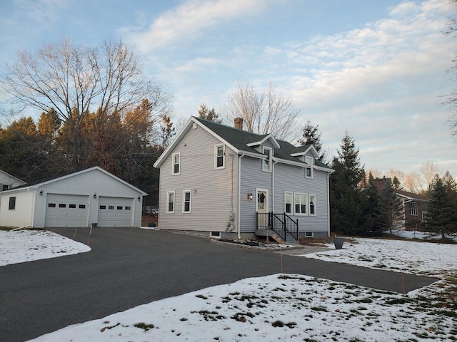 view of snow covered exterior with a garage and an outbuilding