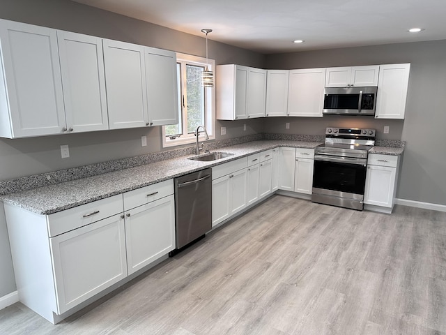 kitchen with white cabinets, decorative light fixtures, sink, and appliances with stainless steel finishes