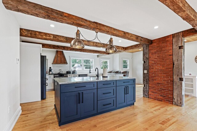 102 Main St, Belgrade, ME 04917 - kitchen featuring black refrigerator, brick wall, beam ceiling, pendant lighting, and a center island with sink