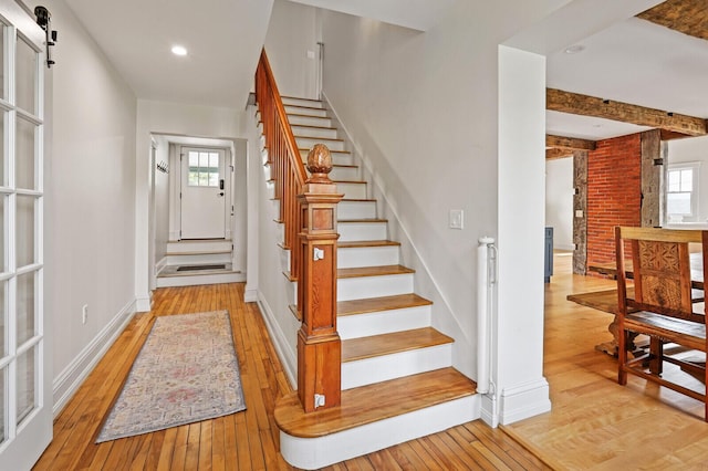 102 Main St, Belgrade, ME 04917 - staircase with beamed ceiling, hardwood / wood-style floors, and a barn door