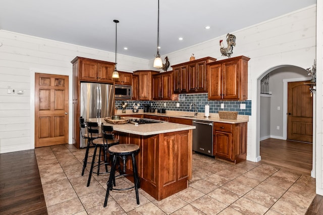 kitchen with sink, tasteful backsplash, decorative light fixtures, a center island, and stainless steel appliances