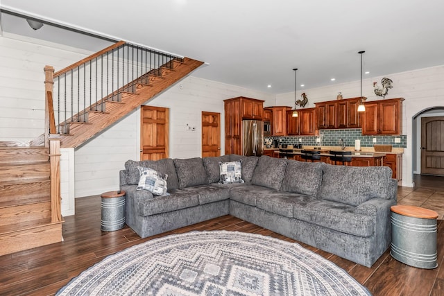 living room with dark wood-type flooring, wooden walls, and sink