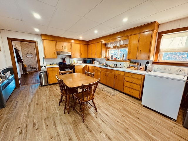 kitchen featuring light wood-type flooring, a paneled ceiling, black appliances, washer / clothes dryer, and sink