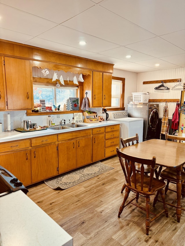 kitchen featuring decorative backsplash, sink, separate washer and dryer, and light hardwood / wood-style flooring