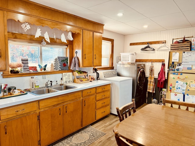 kitchen with washer and clothes dryer, sink, and light hardwood / wood-style flooring