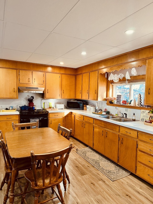 kitchen featuring black appliances, sink, tasteful backsplash, and light hardwood / wood-style floors