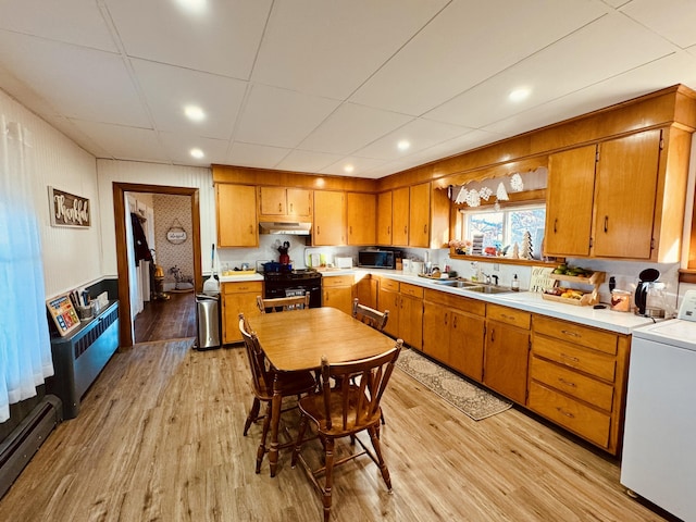 kitchen featuring a baseboard radiator, black appliances, washer / clothes dryer, sink, and light wood-type flooring