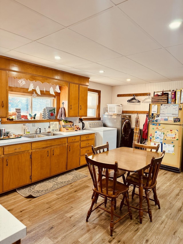 kitchen with washer and dryer, sink, wooden walls, and light hardwood / wood-style floors