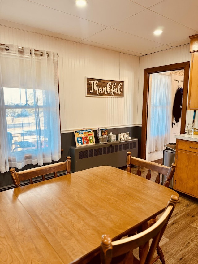 dining area featuring wood walls, wood-type flooring, and radiator heating unit