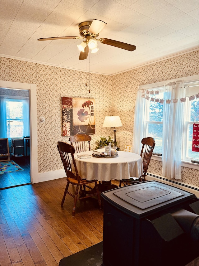 dining space with hardwood / wood-style flooring, a baseboard heating unit, ornamental molding, and ceiling fan