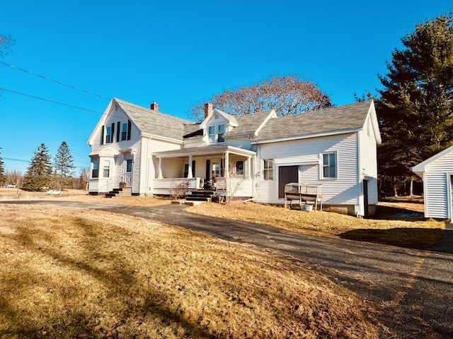 back of house featuring a lawn and covered porch