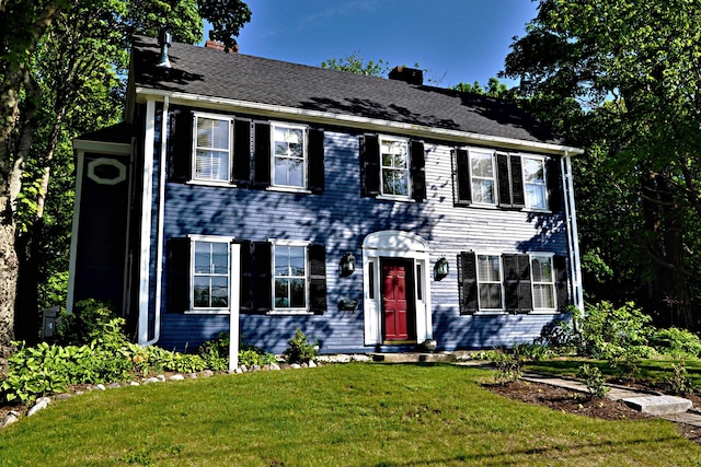 colonial-style house featuring a front lawn