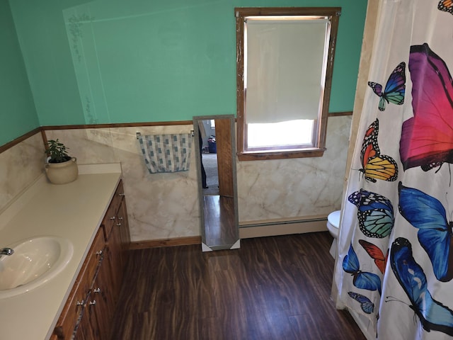 bathroom featuring wood-type flooring, vanity, a baseboard radiator, and toilet