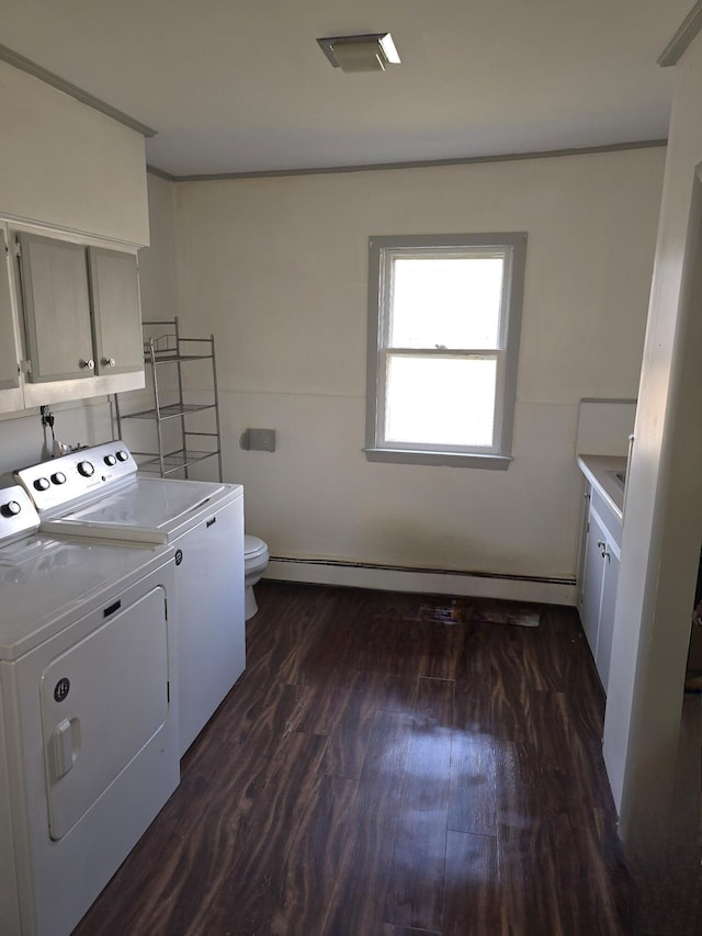 washroom featuring washing machine and dryer, dark hardwood / wood-style flooring, and a baseboard heating unit