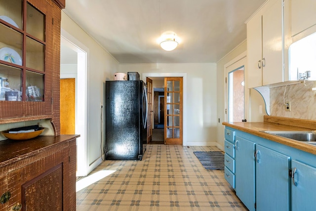 kitchen with white cabinetry, french doors, sink, black fridge, and blue cabinets