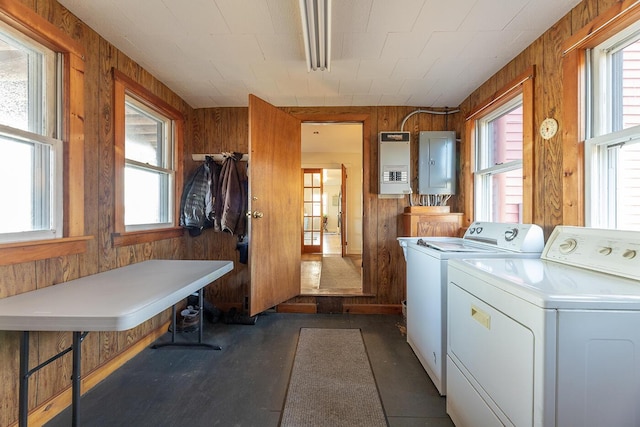 washroom with independent washer and dryer, electric panel, and wood walls