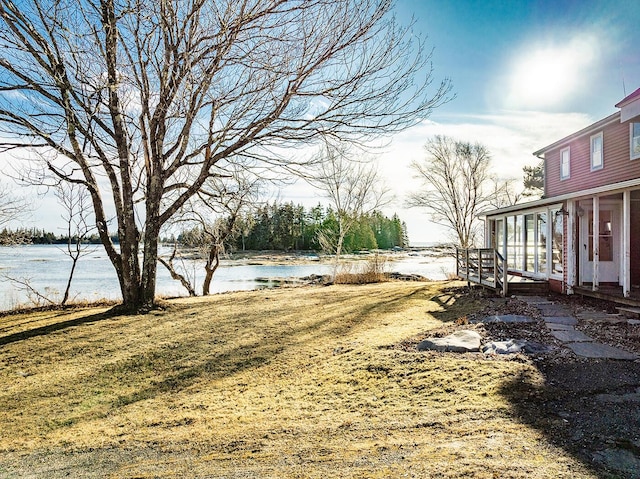 view of yard with a sunroom and a water view