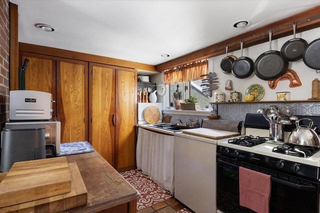 kitchen with sink, dark tile patterned flooring, and gas stove