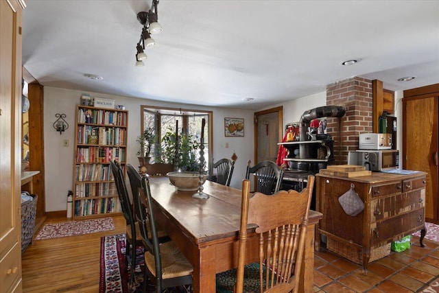 dining room featuring hardwood / wood-style floors, rail lighting, and a wood stove