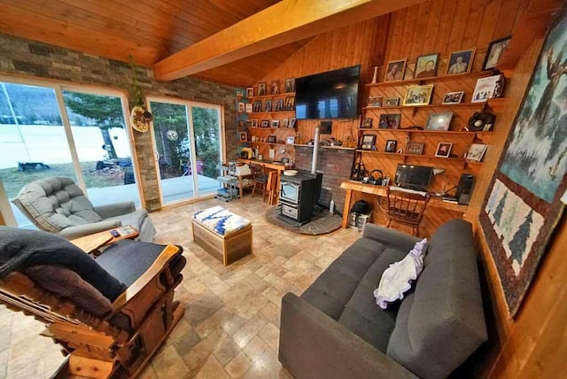 living area featuring lofted ceiling with beams, a wood stove, stone finish flooring, wood walls, and wooden ceiling