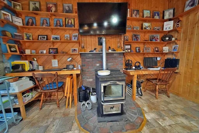 office featuring a wood stove, stone finish floor, and wooden walls