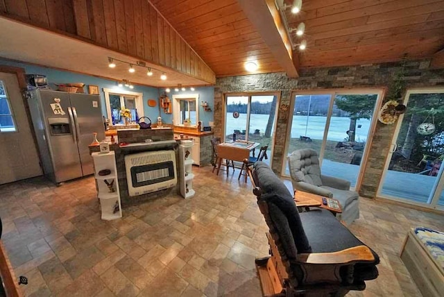 interior space featuring stainless steel refrigerator with ice dispenser, lofted ceiling with beams, wood ceiling, a kitchen island, and track lighting