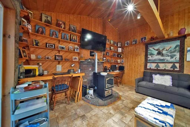 living area with wood ceiling, vaulted ceiling, a wood stove, and wooden walls