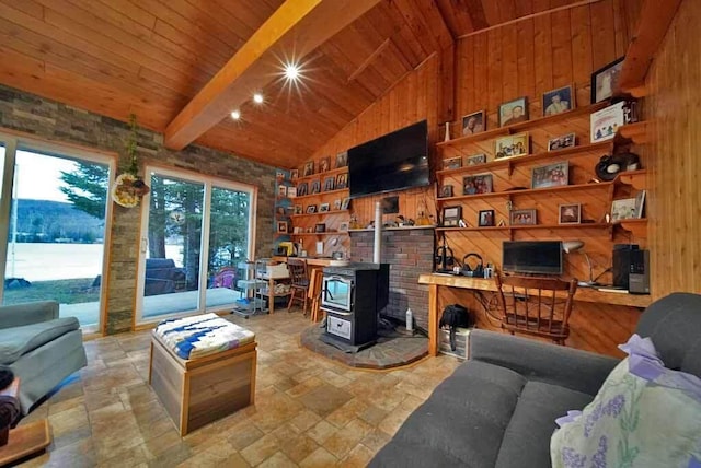 living room with stone tile floors, wooden walls, wooden ceiling, a wood stove, and beam ceiling