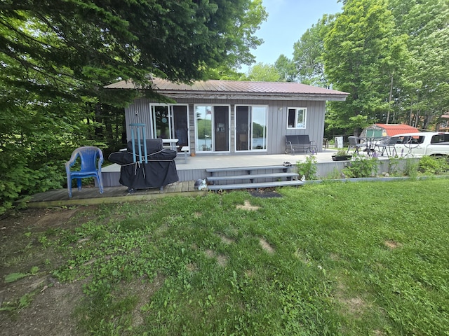 53 Calvin Ln, Oakfield, ME 04763 - back of property with board and batten siding, a yard, a wooden deck, and a metal roof