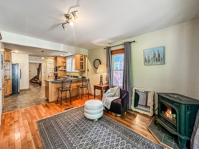 living room featuring track lighting, light hardwood / wood-style floors, a wood stove, and sink