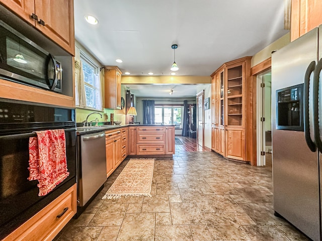 kitchen featuring kitchen peninsula, pendant lighting, black appliances, and sink