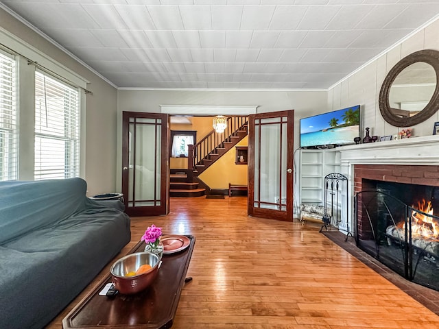 living room featuring a fireplace, crown molding, french doors, and hardwood / wood-style flooring