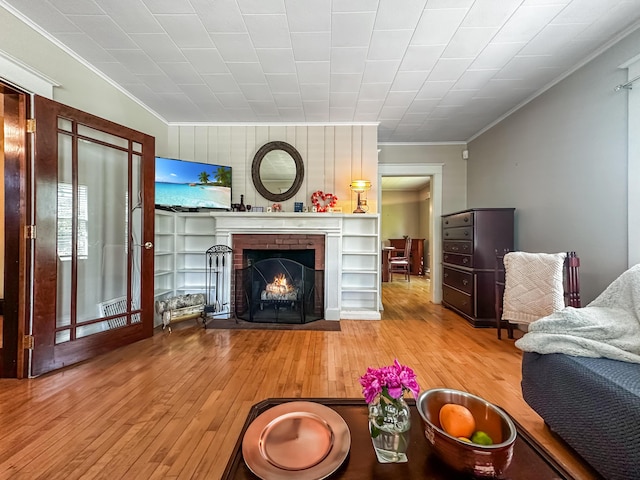 living room featuring light hardwood / wood-style floors, crown molding, and a brick fireplace