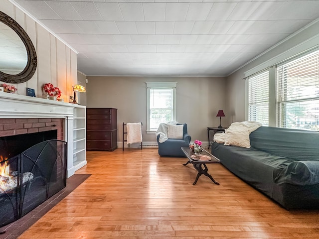 living room with light hardwood / wood-style flooring, a brick fireplace, and crown molding