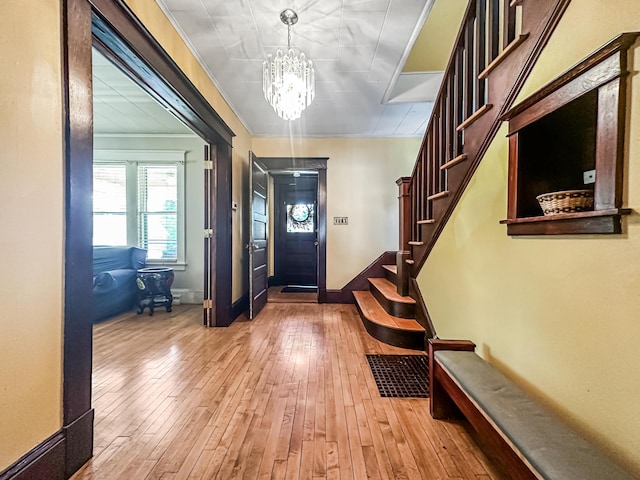 entryway featuring a chandelier, crown molding, and wood-type flooring