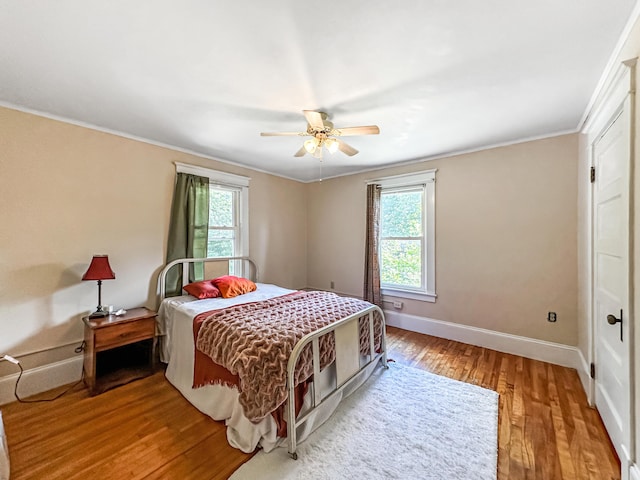 bedroom with hardwood / wood-style floors, ceiling fan, and ornamental molding