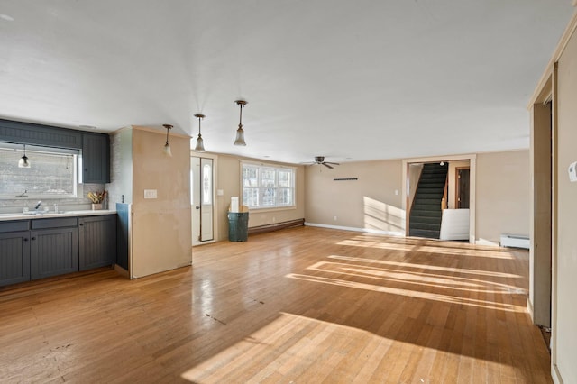 192 Fox Hill Rd, Athens, ME 04912 - unfurnished living room with a sink, baseboard heating, stairway, and light wood-style floors
