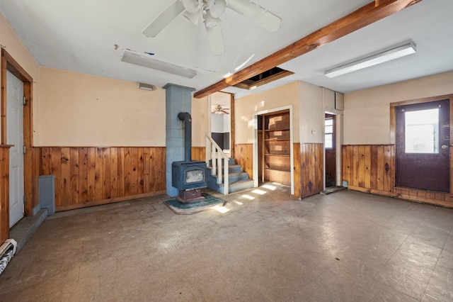 192 Fox Hill Rd, Athens, ME 04912 - unfurnished room featuring a wainscoted wall, a wood stove, wooden walls, ceiling fan, and beamed ceiling